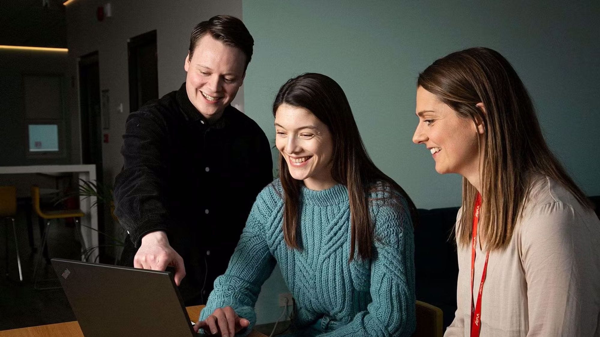 Three people sit by a computer.