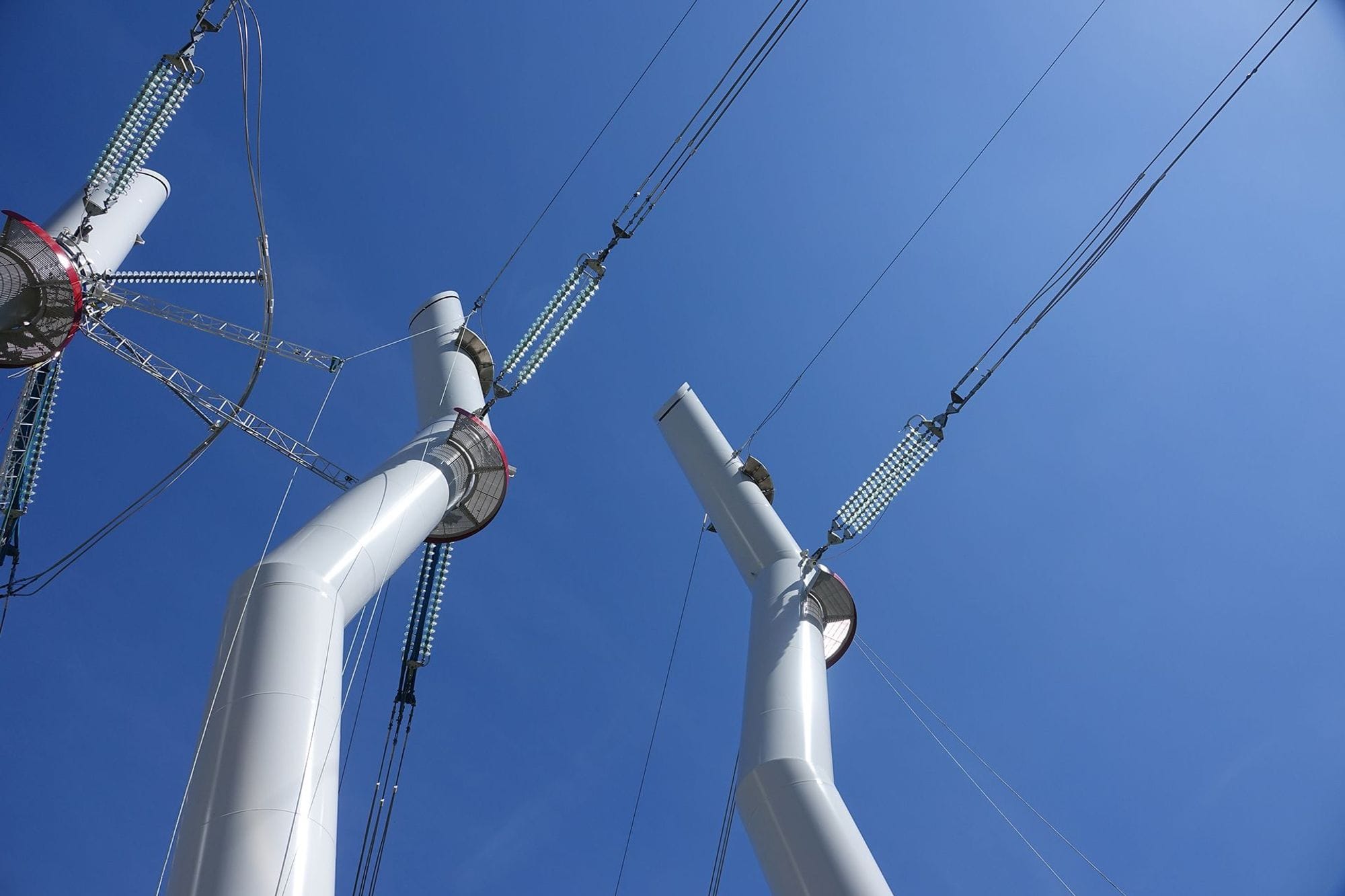 White design masts seen from downside up with blue skies in the background