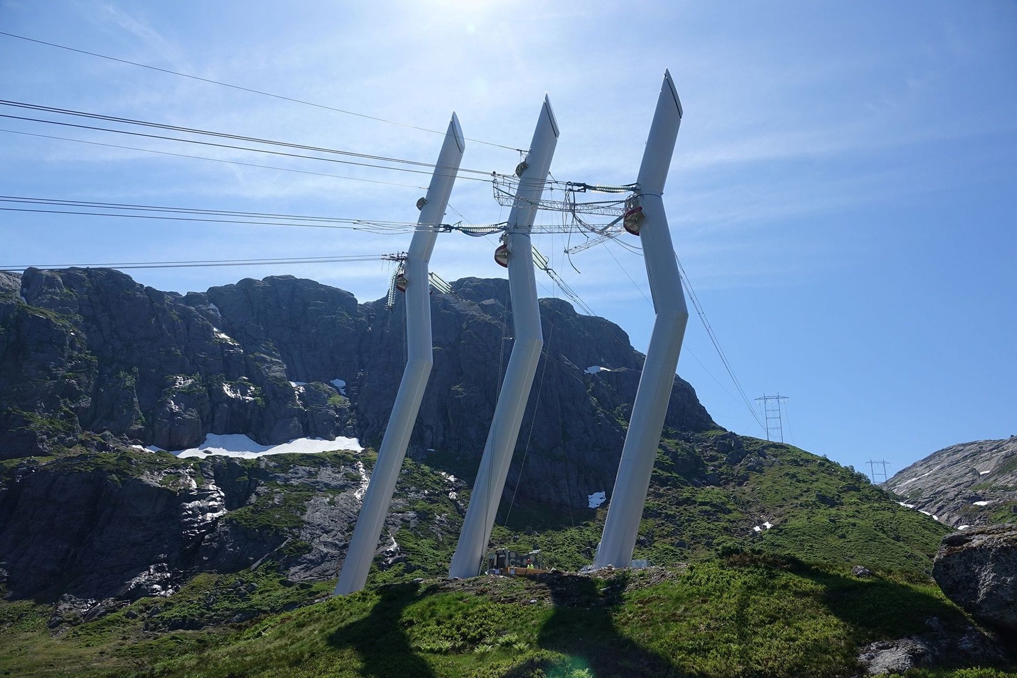 White design masts seen from side with a mountain and blue skies in the background