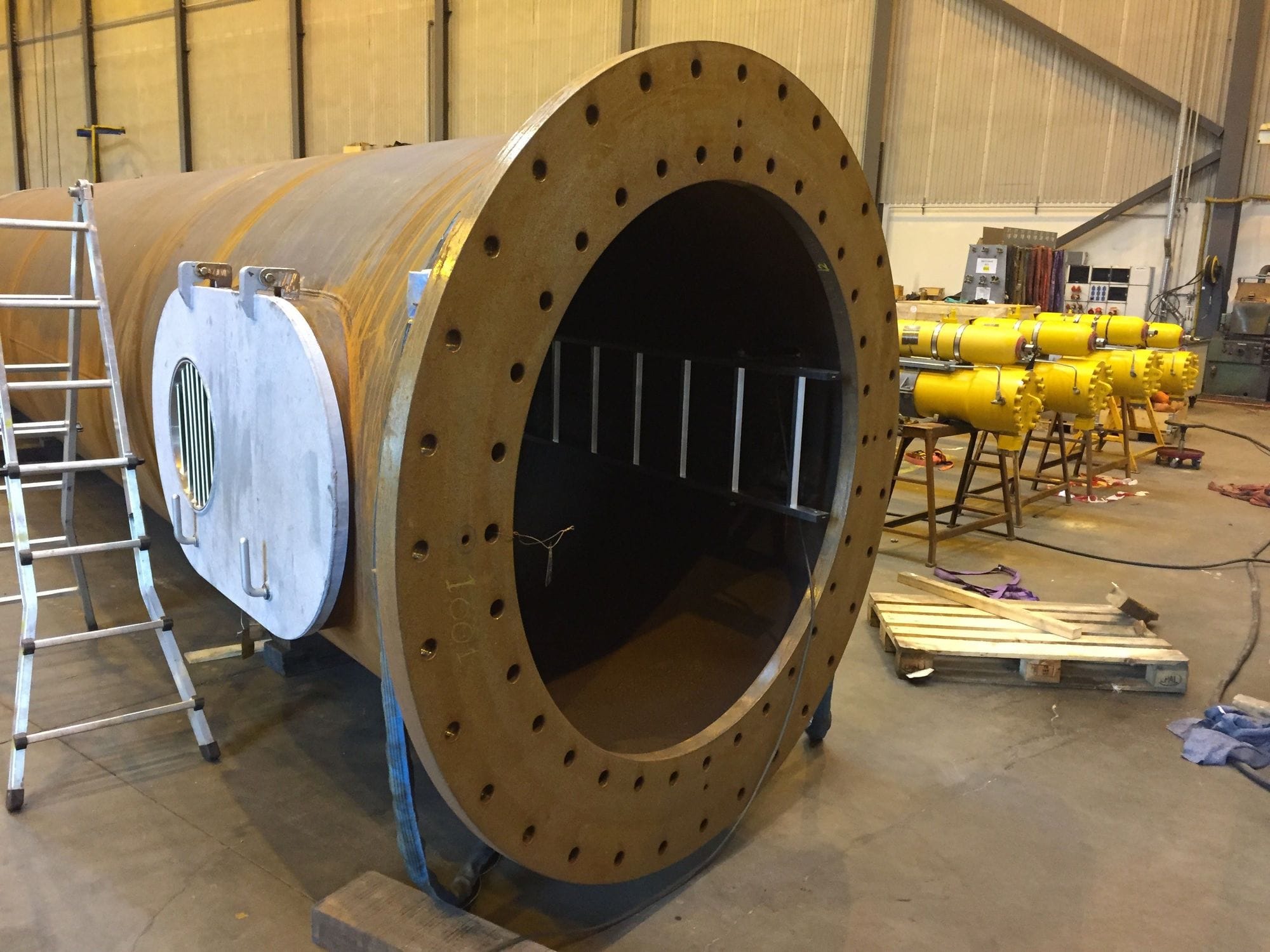 On the front of a large metal tube that is being built inside the workshop