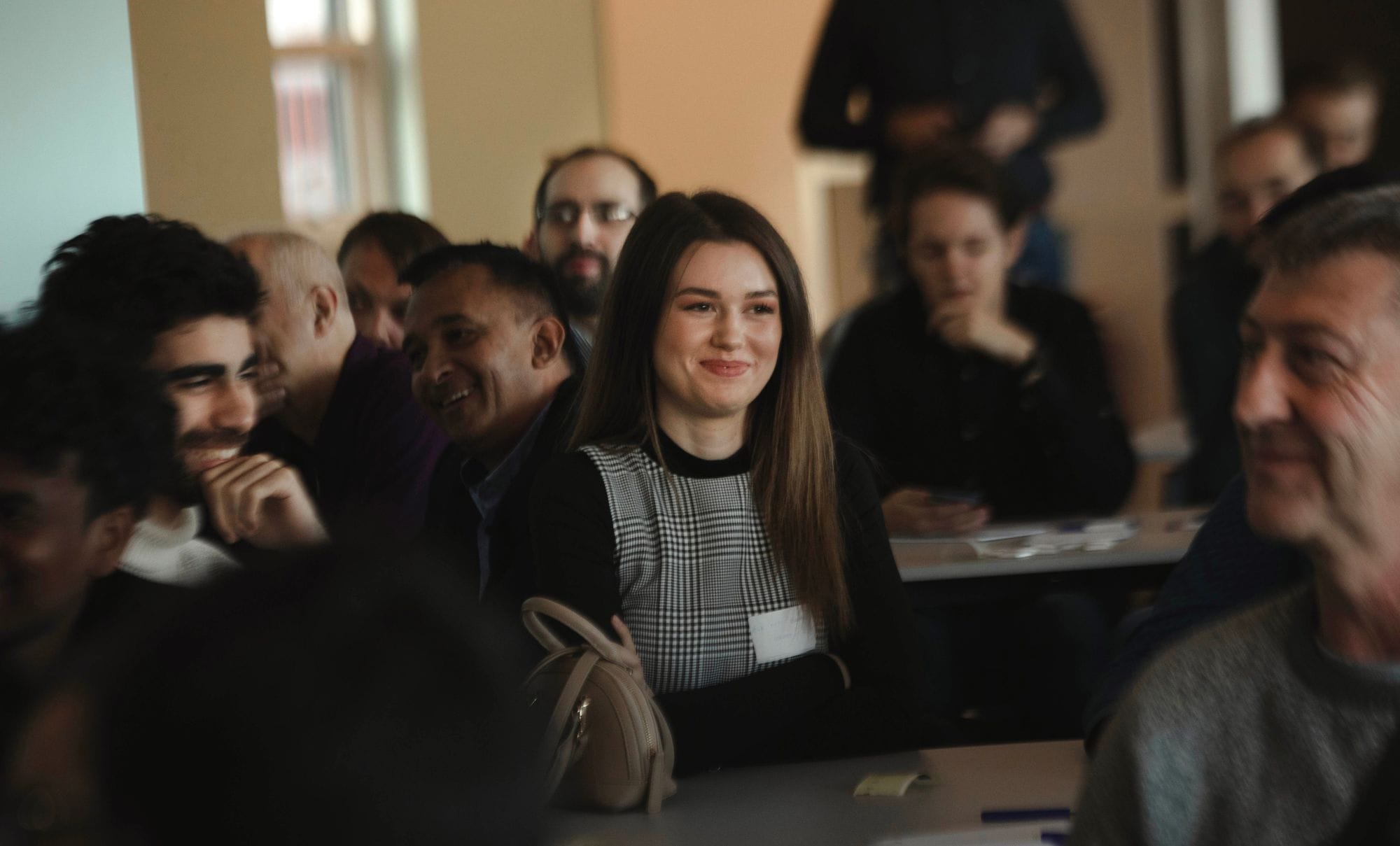 A woman smiling, people sitting around smiling