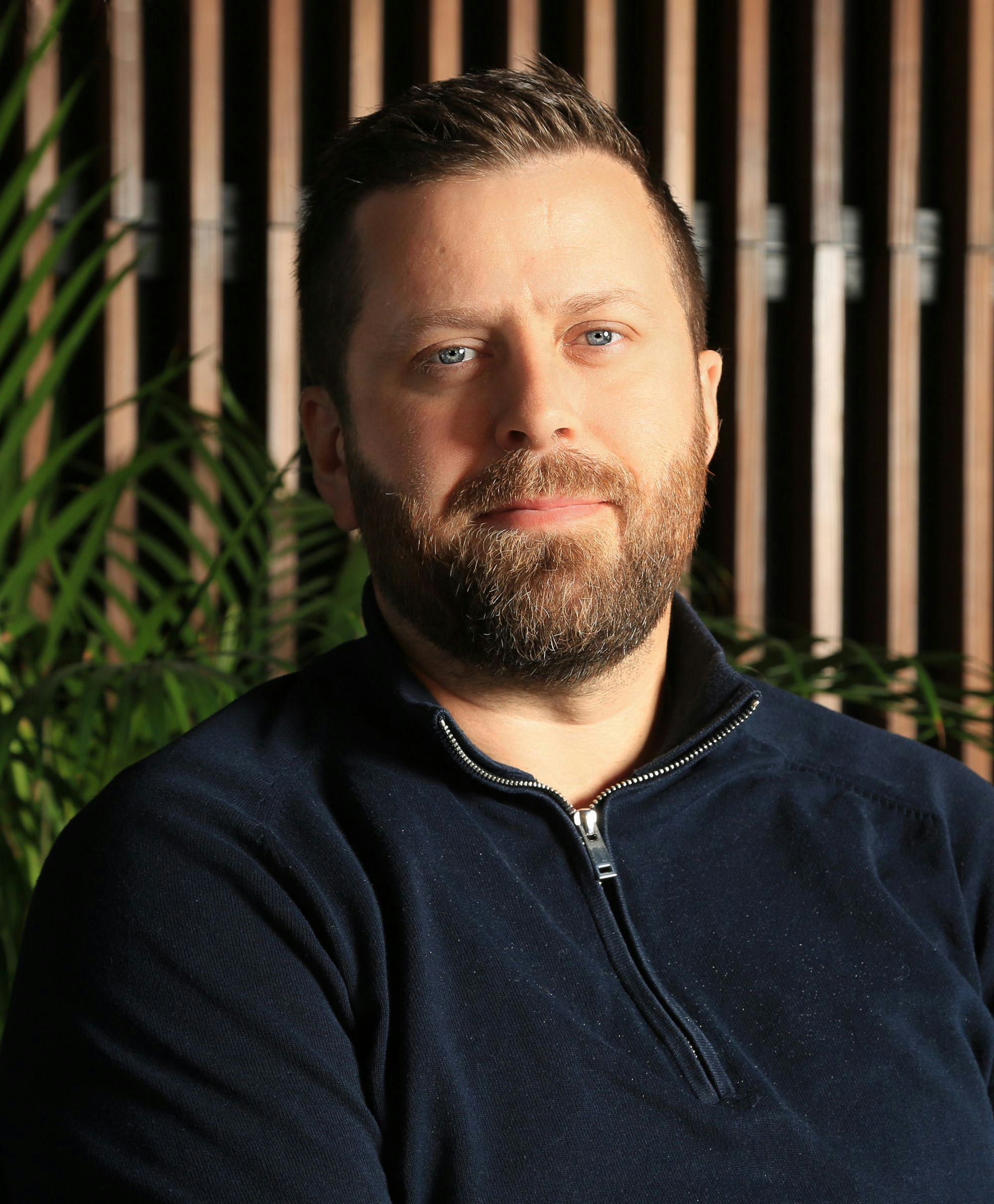 Portrait of a man, green plants and wooden panel in background