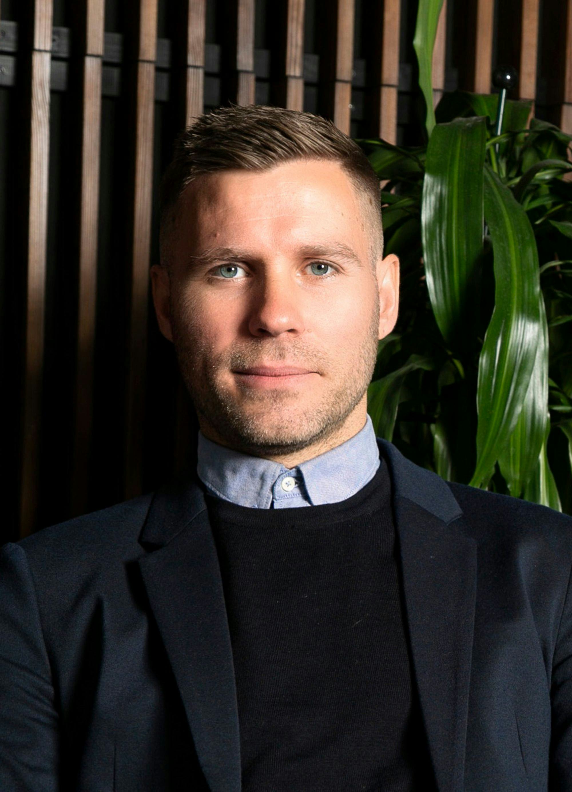 Portrait of a man, green plants and wooden panel in background